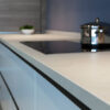 Close-up de encimera Neolith Arena con placa inducción negra, olla y gabinetes azules.