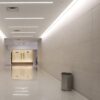 Pasillo largo con paredes y suelo en Neolith Arena beige, iluminación lineal y persona al fondo.