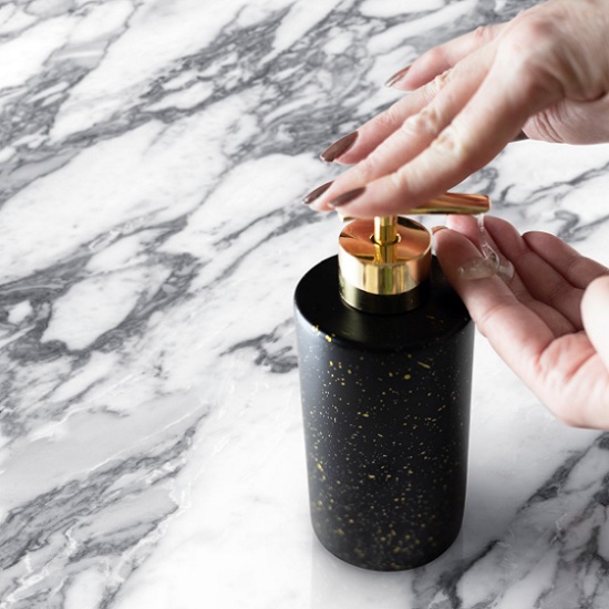 primer plano de una encimera Neolith Arabesque y una mano con una jabonera