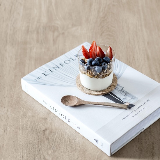un libro blanco y un recipiente con postre sobre una encimera de cocina Neolith Summer Dala