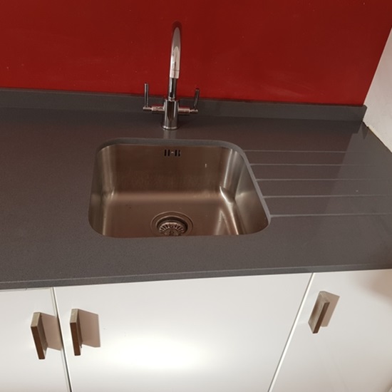 una encimera Cuarzo Plomo Grey pulido en una cocina con pared roja