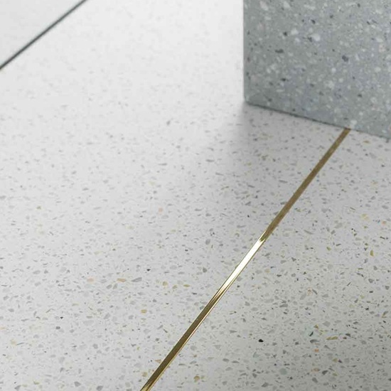 suelo terrazo crema con tira metálica dorada Krion Marmo Bianco
