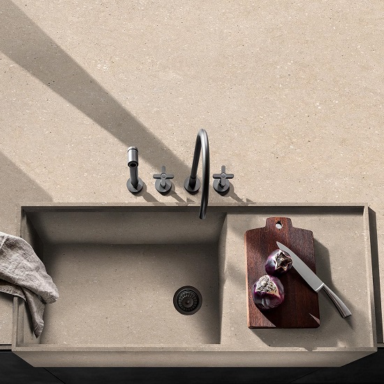 Vista superior de fregadero en encimera Arklam Bateig Verona beige con tabla, cuchillo y cebolla en cocina minimalista.