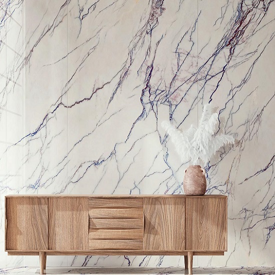 Sala con pared Arklam Lilac blanca veteada, mesa y jarrón en ambiente luminoso.