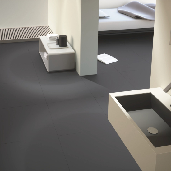 Suelo Neolith Basalt Grey en baño minimalista Málaga, superficie gris resistente con lavabo blanco.