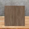Muestra cuadrada de Arklam Canada madera marrón sobre mesa de madera, con veta visible.