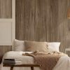 Dormitorio con pared Arklam Canada madera marrón, cama blanca con manta y libros en mesita.