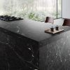 : Isla de cocina con encimera Arklam Caviar Green en Málaga, equipada con fogones y accesorios modernos.