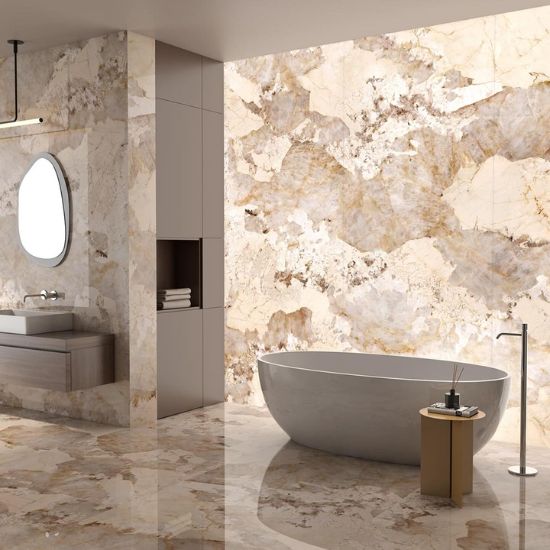 Baño de lujo con revestimientos y encimeras Arklam Patagonia Gold en Málaga, bañera gris y accesorios madera.