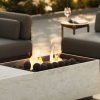 Brasero exterior en Dekton Nara con llamas vivas y bolas negras, en entorno de terraza lounge.