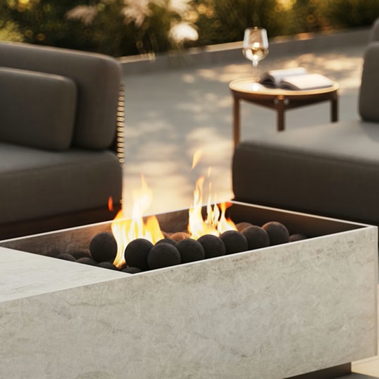 Brasero exterior en Dekton Nara con llamas vivas y bolas negras, en entorno de terraza lounge.