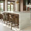 Isla de cocina minimalista en Dekton Nara con iluminación colgante, sillas y paredes a juego.