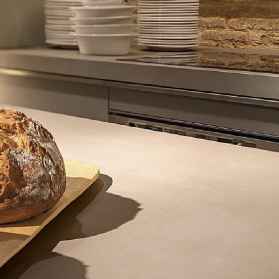 Encimera Neolith Barro terracota con pan fresco sobre tabla de cortar en cocina con estantes.