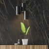 Pared revestida Neolith Black Obsession Málaga, superficie negra dorada con iluminación y vegetación.