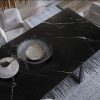 Mesa de comedor Blaker Total Cosmic Black negra veteada con sillas grises, bol y rama en sala moderna.