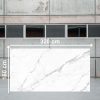 Losa grande de Blaker Statuario Grey blanca veteada en entorno industrial interior.