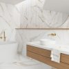 Baño spa con bañera blanca, grifo bronce, espejo redondo y revestimientos Blaker Venatino Gold blancos con vetas doradas.
