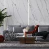 Sala contemporánea con pared Blaker Venatino Grey blanca veteada, sofá gris, mesa bronce y flores en diseño moderno.