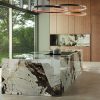 sla de cocina Venux Arctic Patagonia blanca veteada con olla, gabinetes de madera y vista ventana en ambiente moderno.