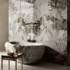 Baño spa con bañera de piedra, grifo plateado y revestimientos Venux Arctic Patagonia blancos con vetas marrones.