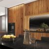 Cocina moderna con gabinetes Blaker Caoba marrón, isla negra con jarrón y frutas en ambiente luminoso.