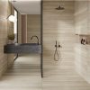 Baño moderno con ducha de vidrio, lavabo negro y revestimientos Blaker Flaminio Dak beige con vetas travertino.