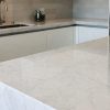 Cocina con encimera de mármol Arctic White, incluyendo isla y salpicadero, para aplicaciones decorativas.