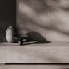 Baño moderno con encimera de baño Venux Bellissima Grigio gris veteado, espejo redondo, grifo bronce y productos en ambiente cálido.