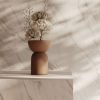 Baño moderno con encimera de baño Venux Calacatta Classic blanca veteada, espejo redondo, grifo dorado y toalla en ambiente cálido.