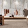 Sala moderna con credenza Venux Calacatta Gold blanca veteado, sillas grises, mesa redonda y decoración en ambiente sereno.