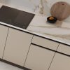 Vista cercana de encimera Venux Calacatta Gold blanca veteada con tabla de cortar, limón y libro en cocina moderna.