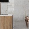 Cocina moderna con isla Venux Aurora Crystal blanca veteada, taburetes madera y gabinetes blancos en ambiente luminoso.
