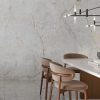 Sala con mesa de comedor Venux Aurora Crystal blanca veteada, sillas marrones y lámparas doradas en ambiente elegante.