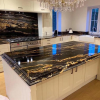Cocina completa con isla grande en Granito Black Taurus, muebles blancos y araña de cristal