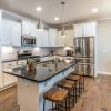 AlternativoIsla de cocina moderna con encimera de Granito Cosmic Black, granito negro con vetas blancas, muebles blancos y taburetes de madera
