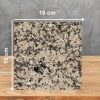 Muestra 10 x 10 cm de Granito Crema Camelia sobre superficie de madera