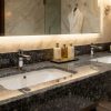 Mueble de baño flotante en Granito Gris Quintana con lavabo blanco, grifería cromada y bañera exenta