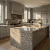 Isla de cocina en Granito Mondariz con muebles gris claro y grifería dorada