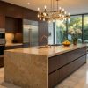 Isla de cocina larga en Granito Sahara Gold con muebles oscuros y grifería dorada